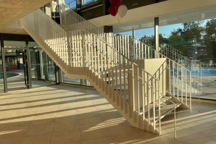 Foyer-Treppe mit Zwischenpodest und beidseitigem Geländer, weiß lackiert von Stahlbau Nägele.